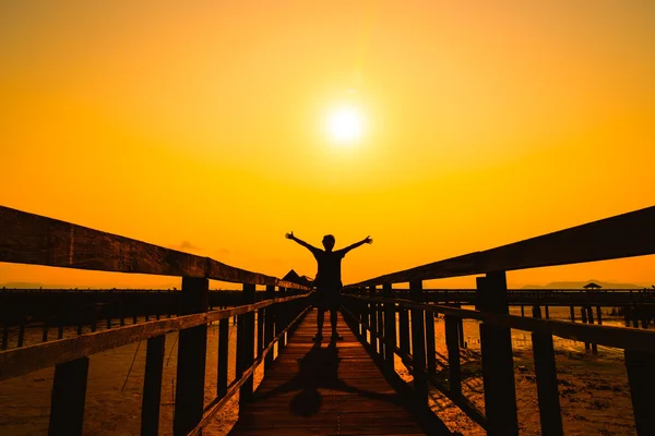 Glücklicher freier Mann Silhouette auf Holzbrücke bei Sonnenuntergang. — Stockfoto