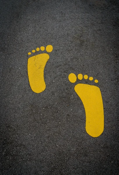 Yellow footprint on an asphalt road. — Stock Photo, Image