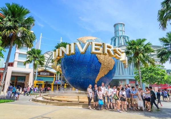 Singapur - 9 Temmuz: Turist ve Universal Studios önünde büyük dönen küre çeşme 9 Temmuz 2014 Sentosa Island, Singapur fotoğraflarını Tema parkı ziyaret edenler