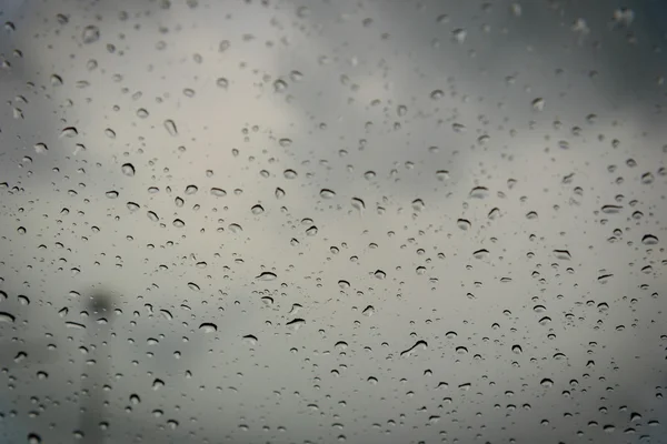 Gotas de lluvia en el cristal de una ventana. Profundidad de campo superficial. Enfoque selectivo . — Foto de Stock
