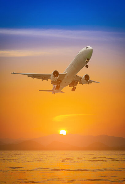 Plane flying above mountain at during sunset.