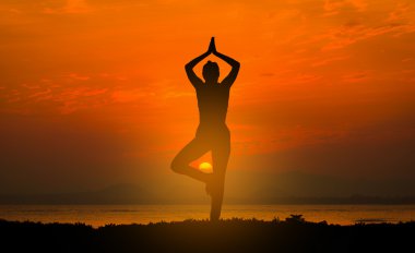 gün batımında sahilde Yoga uygulamak siluet genç kadın.
