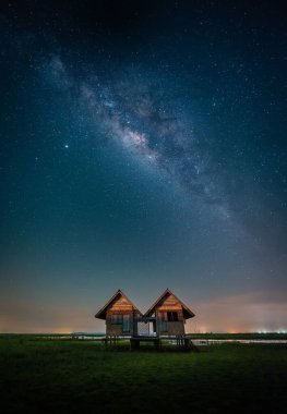 Thale Noi, Phatthalung, Tayland 'daki Chalerm Phra Kiat yolunun yakınındaki terk edilmiş ikiz evin üzerindeki samanyolu manzarası.