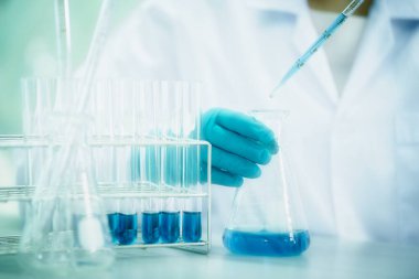 Doktor ya da bilim adamı, tıbbi araştırma laboratuarına ya da bilim laboratuarına numune bırakmak için pipette kullanıyor.