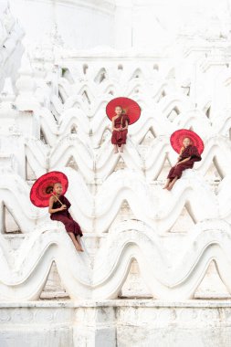 MANDALAY, MYANMAR, -11 Aralık 2017: Mingun, Mandalay Myanmar 'daki Mya Thein Tan Pagoda' da elinde kırmızı şemsiyeler tutan tanımlanamayan Asyalı genç keşiş.