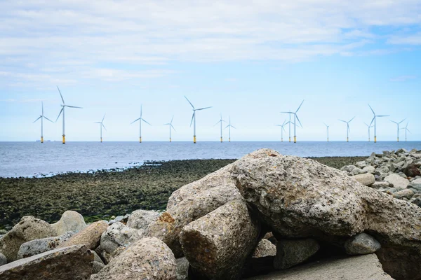 Stones on the beach and wind turbine background — Stock Photo, Image