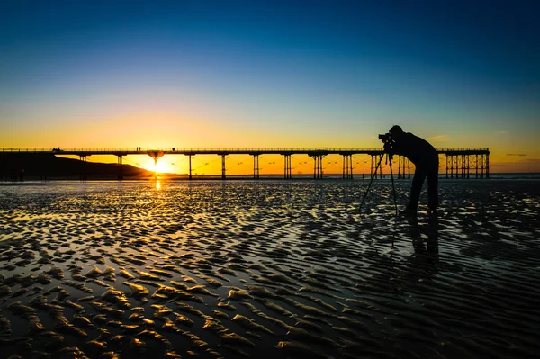 Silhouet van een fotograaf op de prachtige zonsondergang of zonsopgang op pier — Stockfoto