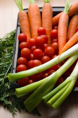 Bir tavada bir ahşap plaka üzerinde taze sebze.