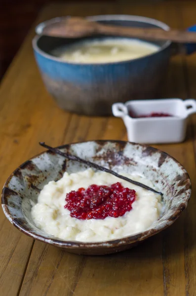 Milky rice on a wood table with homemade raspberry jam and vanilla. — Stock Photo, Image