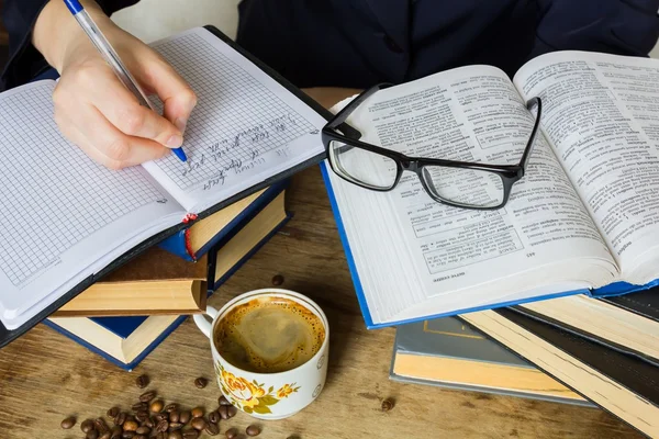 Kitap yığını yakınındaki masada oturan kız