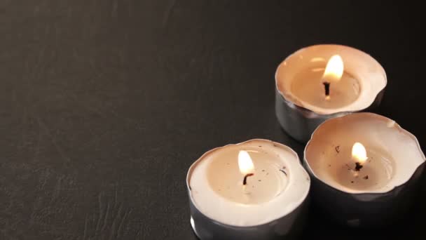 Três velas redondas em um fundo preto — Vídeo de Stock