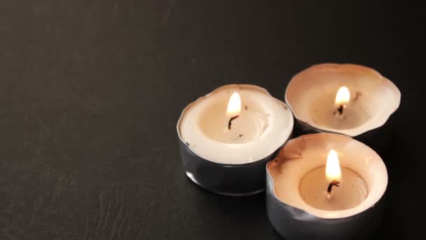 Три круглых свечи на черном фоне — стоковое видео