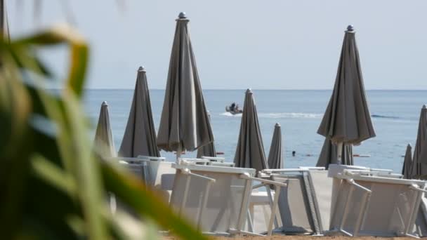 Tomma stranden på kusten av en badort, ensamma solstolar och nära grå strand parasoller, slet bort badorten på grund av covid 2019, coronavirus, karantän, Adriatiska havet, Montenegro — Stockvideo