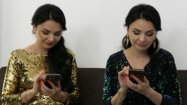 Αστείο παράξενο βίντεο με μια γυναίκα σε ένα αξιολάτρευτο βραδινό φόρεμα σε χρυσό και μπλε, με φωτεινό μακιγιάζ με αποτέλεσμα δίδυμα πληκτρολογώντας κάτι στο τηλέφωνο και μιλώντας — Αρχείο Βίντεο