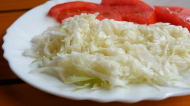 Vejetaryen menüsü, lahana salatası ve domates dilimleri yemek odasındaki masada.