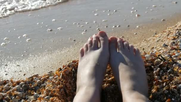 Los pies femeninos, los dedos de los pies en la playa de concha marina, el mar y las olas. Concepto de relajación, vacaciones de verano. POV — Vídeos de Stock