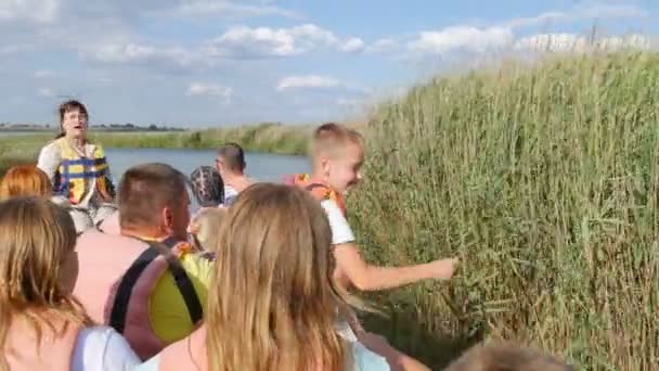 Genichesk, Ucrania - 2 de agosto de 2020: Un guía turístico en un barco de recreo cuenta historias a los turistas que llevan chalecos salvavidas. Excursión al lago Sivash Entre los matorrales de juncos — Vídeos de Stock