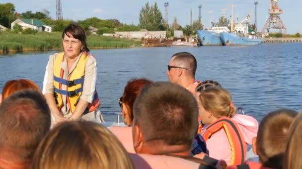 Genichesk, Ucrania - 2 de agosto de 2020: Un guía turístico en un barco de recreo cuenta historias a los turistas que llevan chalecos salvavidas. Excursión al lago Sivash — Vídeo de stock