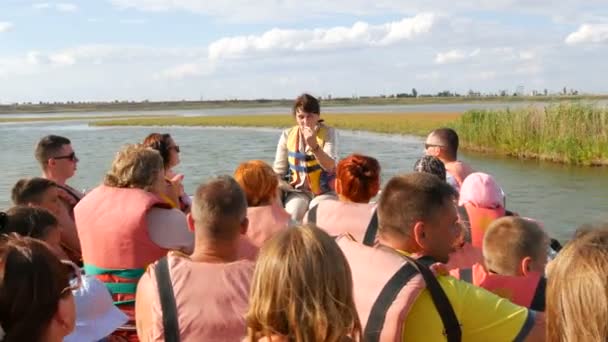 Genichesk, Ukraine - 2. August 2020: Ein Reiseleiter auf einem Ausflugsboot erzählt Touristen in Schwimmwesten Geschichten. Sivash See Exkursion Inmitten des Schilfdickichts — Stockvideo