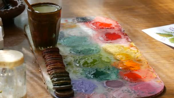 Petrykovka, Ukraine - October 14, 2020: palette with different paint colors, different brushes and paints for painting on the table in the artists studio — Stock Video