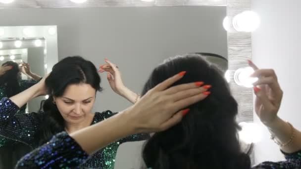 Giovane bella donna fa i capelli davanti allo specchio. Lunghi capelli neri — Video Stock