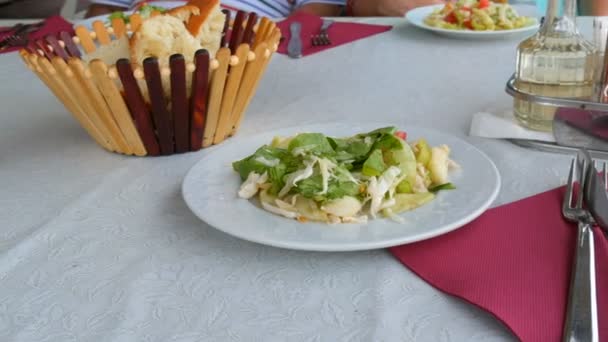 Nastavení stolu v restauraci. Chléb v košíku, zeleninový salát v talíři, nožířský nůž, vidlička, lžička na červeném ubrousku — Stock video