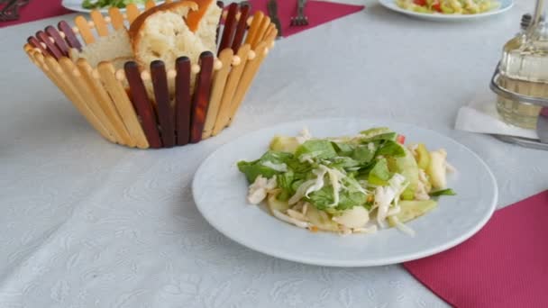 Lokantada masa ayarlandı. Sepette ekmek, tabakta sebze salatası çatal bıçak, kırmızı peçetede kaşık. — Stok video