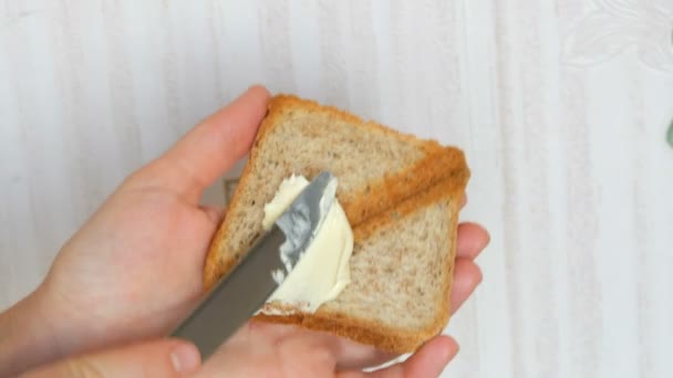 En kvinnlig hand sprider smör med en bordskniv på rostat bröd. Morgonfrukost — Stockvideo