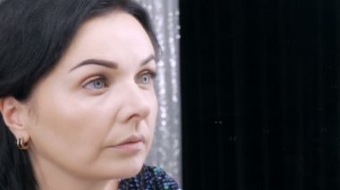 Aynanın önündeki güzel, gösterişli genç kadın özel bir fırçayla yüz ve göz makyajı yapıyor.