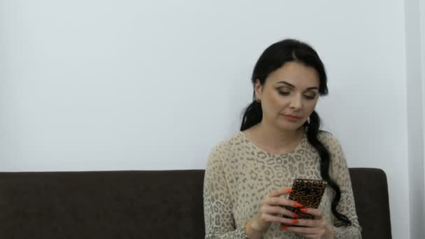 Krásná mladá žena s večerní make-up tiskne něco na telefonu v místnosti — Stock video