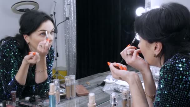 Mladá krásná showy žena v přední části zrcadla aplikuje tvář a oční make-up se speciálním štětcem — Stock video