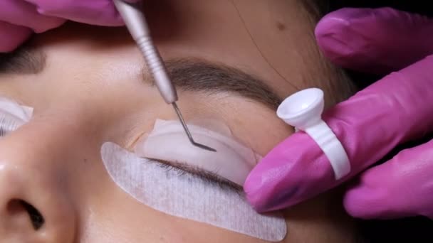 Face of a young girl on a modern eyelash lamination procedure in beauty salon. The master applied special chilicone patches and straightened eyelashes to the eyes during the eyelash curling procedure — Stock Video