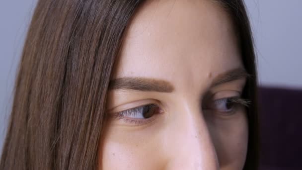 Het gezicht van een jong meisje voor een moderne wimper lamineren procedure in een professionele schoonheidssalon voor de wimper curling procedure. Portret van een vrouw zonder make-up met donkere lippenstift — Stockvideo