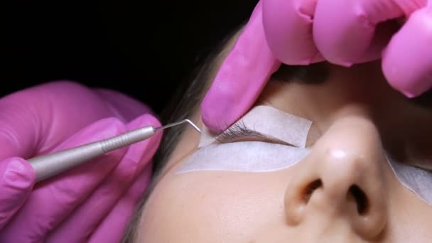 Modern eyelash lamination procedure in a professional beauty salon. The master puts the eyelashes on special adhesive patches using a special needle before the eyelash curling procedure — Stock Video