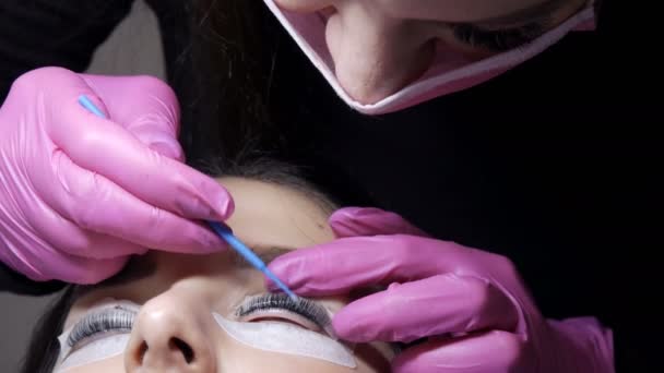 Gesicht des jungen Mädchens vor der Wimpernlaminierung in einem professionellen Schönheitssalon. Beim Wimpernrollen wäscht der Meister die schwarze Farbe auf den Wimpern mit einem speziellen Pinsel ab — Stockvideo