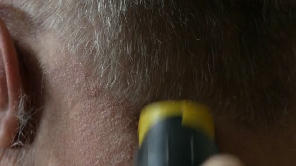 Corte de cabelo de um idoso sem-abrigo com um cortador especial. As mãos femininas cortam cabelos grisalhos de um homem vista de perto — Vídeo de Stock