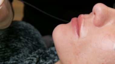 Kozmetoloji kliniğindeki dudak rengini düzelten özel renk pigmentli mikro patenli dudak dövmesi. Eller, dövme makinesiyle dudaklara pigment makyajı uygulayarak kalıcı makyaj yapar.