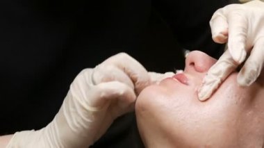 Kozmetoloji kliniğindeki dudak rengini düzelten özel renk pigmentli mikro patenli dudak dövmesi. Eller, dövme makinesiyle dudaklara pigment makyajı uygulayarak kalıcı makyaj yapar.