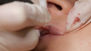 Kozmetik uzmanı, dövme makinesi pembe pigmenti kullanarak dudaklarını mikro patinaj yaptırıyor. Kadın dudaklarına pigment makyajı yapan bir güzellik uzmanı. Güzellik salonunda güzellik endüstrisi kavramı