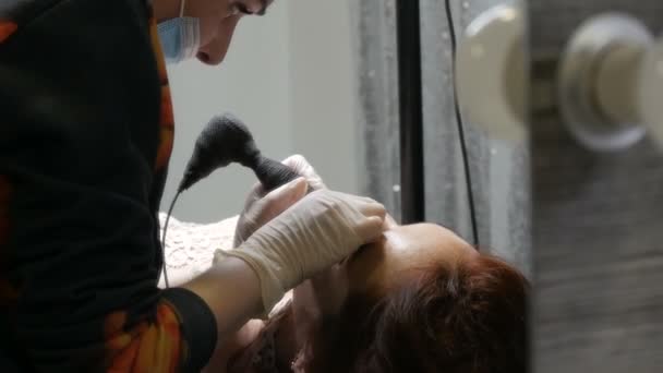 Cosmetologist mãos fazendo lábios microblading procedimento permanente usando pigmento rosa máquina de tatuagem. Esteticista aplicando maquiagem pigmento em lábios de mulher. Conceito da indústria da beleza no salão de beleza — Vídeo de Stock
