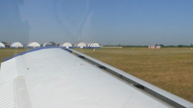 Dnipro, Ukrayna - 5 Temmuz 2020: Küçük bir yolcu uçağı havaalanındaki hangar ve diğer uçaklara karşı kalkışa hazırlanıyor. Pencere ve kanattan görüntüle