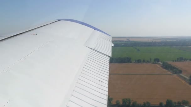 在白色机翼的背景下，从一架小型私人客机的窗口观看。俯瞰黄色的田野，绿林 — 图库视频影像