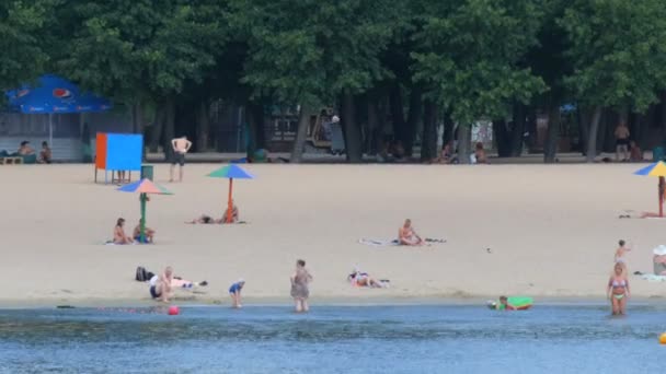 Zaporizhzhia, Ukrajna - június 19, 2020: Vitorlázás mellett a város strandján, amely ritkán zsúfolt az emberek, akik sütkéreznek a napon. Kilátás a folyó vagy a tó oldaláról. Napozás a karantén alatt. — Stock videók