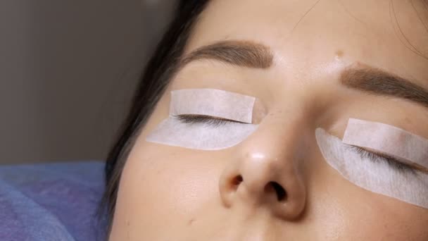 Modern eyelash lamination procedure in a professional beauty salon. The master sticks special adhesive patches on the eyes before the eyelash curling procedure — Stock Video