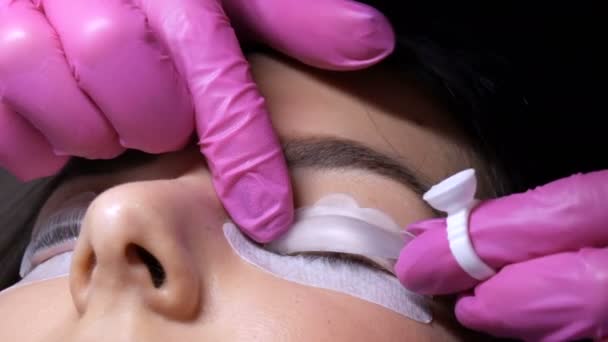 Modernes Wimpernkaschierverfahren in einem professionellen Schönheitssalon. Der Meister trägt vor dem Wimpernkräuseln spezielle Silikonwickler auf — Stockvideo