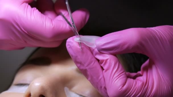 Modernes Wimpernkaschierverfahren in einem professionellen Schönheitssalon. Der Meister schneidet vor dem Wimpernkräuseln spezielle Silikon-Lockenwickler auf die Größe des Auges — Stockvideo