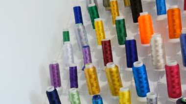 Dikiş makinesi için bir sıra çok renkli iplik ve dikiş atölyesi ya da atölyesinde kilit. Endüstriyel dikiş makinesinde farklı renk ipliklerinin makaralarını ayarlar.