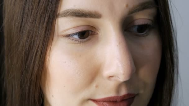 El rostro de una joven antes de un procedimiento moderno de laminación de pestañas en un salón de belleza profesional antes del procedimiento de rizado de pestañas. Retrato de una mujer sin maquillaje con lápiz labial oscuro — Vídeos de Stock