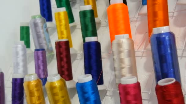 Una fila di fili multicolori diversi per una macchina da cucire e overlock in un laboratorio di cucito o atelier. Righe bobine di filo di diversi colori nella macchina da cucire industriale. — Video Stock