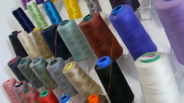 Ряд різнокольорових різнокольорових ниток для швейної машини та оверлоку в швейній майстерні або ательє. Рядки кульок ниток різних кольорів в промисловій швейній машині . — стокове відео